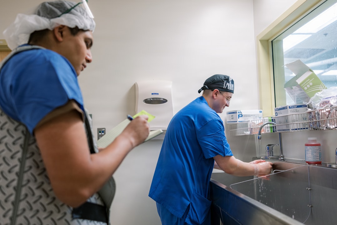 Hand Hygiene Observation at U.S. Naval Hospital Guam. Hospital Corpsman 3rd Class Amaya, Aiden, the Main Operating Room Hand Hygiene Representative, observes Hospital Corpsman 3rd Class Kirkpatrick, Aiden, a surgical technologist, performing his first surgical scrub of the day in the main operating room at U.S. Naval Hospital Guam, Dec. 16, 2025. Proper hand hygiene and surgical scrub practices are critical infection prevention measures that support patient safety and ensure the delivery of high-quality surgical care. (U.S. Navy photo by Hospital Corpsman 1st Class Clien Lester Guico.)